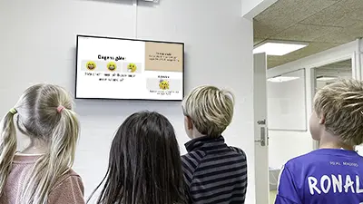 Barneskole-elever studerer 'dagens gåte' på infoskjermen i gangen